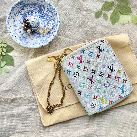 An authentic vintage Louis Vuitton mini agenda zippe  in the brand's classic white multicolor monogram canvas, featuring a gold-tone chain strap, displayed on a beige dust bag.